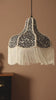 A video of the leopard print tassel ceiling light hanging in front of a plain background with a sideboard and a plant.