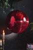 A video of the Red Disco Ball spinning, styled with lit candles, greenery and books.
