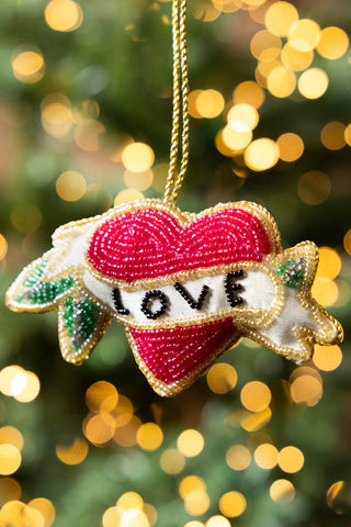 The Love Heart Beaded Hanging Christmas Tree Decoration hanging in front of blurred fairy lights.