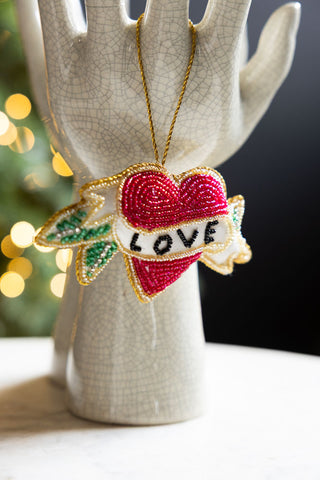 The Love Heart Beaded Hanging Christmas Tree Decoration styled hanging from a ceramic sculpture.