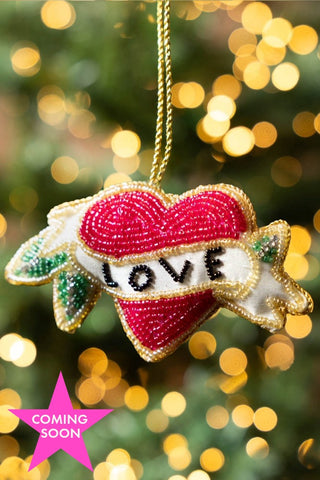The Love Heart Beaded Hanging Christmas Tree Decoration hanging in front of blurred fairy lights. Image shown with a pink heart icon that reads 'coming soon'.