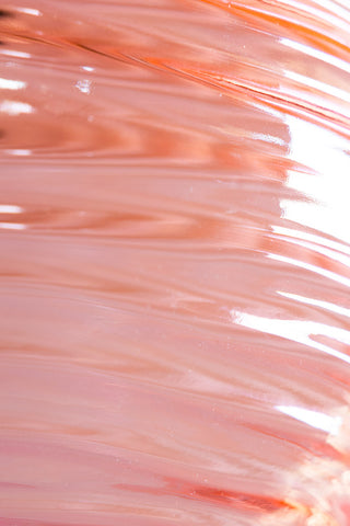 Close up detail image of the Swirled Glass Easyfit Ceiling Light Shade in Pink against a white wall, showing glass texture.