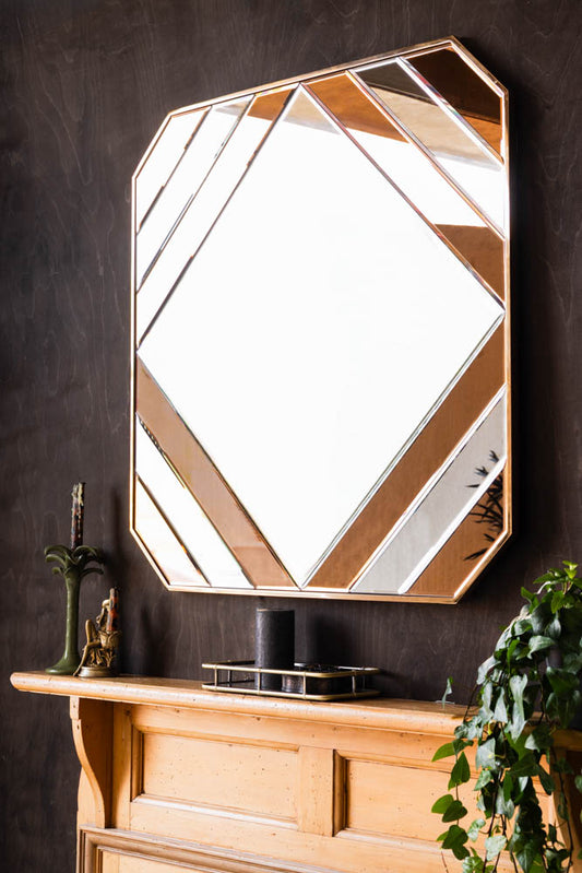 The 70s-inspired Copper Wall Mirror on the wall above a fireplace, with a plant and various accessories.