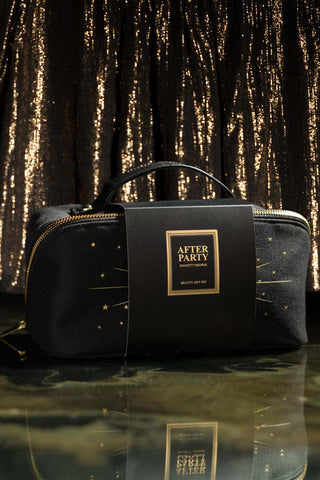The After Party Makeup Bag Beauty Gift Set in its packaging, displayed on a dark surface in front of a metallic background.