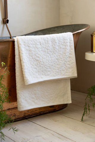 Close up of one of the large Leopard Jacquard Towel in Almond against a copper bath tub.