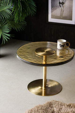 Lifestyle image of Amber Glass Coffee Table styled with a mug and plant. 