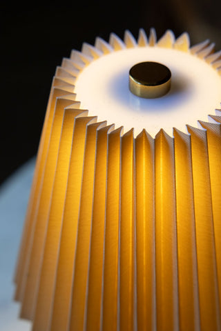 Close-up of the top of the Amber Pleated Rechargeable Table Lamp, switched on.