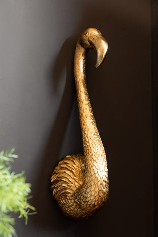 Image of the Antique Gold Flamingo Head Wall Art shown against a dark wall. 