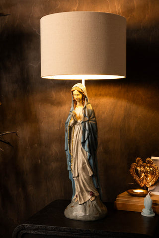 The Antique-Style Santa Maria Table Lamp switched on and styled on a sideboard in front of a dark wall.