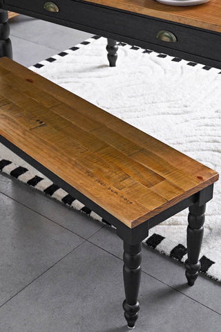 A close up image of the Apothecary Bench tucked under a table on a white rug. 