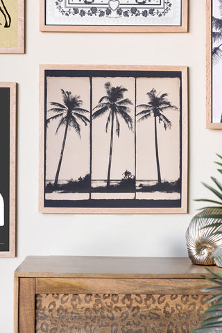 Framed artwork of palm trees on a wall with decorative elements.