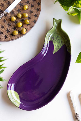 The Aubergine Serving Plate displayed on a white table alongside a star serving board, cutlery, olives and a plant.