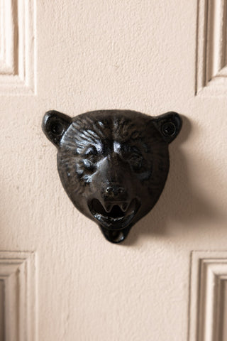 A head on shot of the Bear Head Wall Mounted Bottle Opener, shown attached to a door. 
