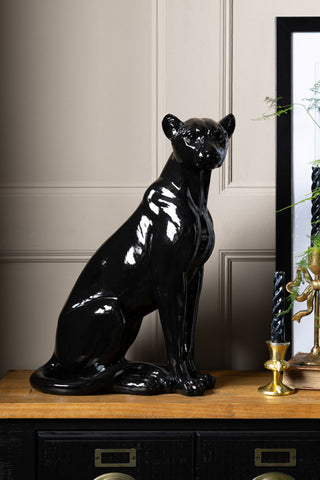 The Beautiful Black Panther Decorative Ornament styled on a wooden sideboard with some candles, a framed artwork and a plant.