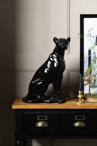 The Beautiful Black Panther Decorative Ornament styled on a wooden table with some home accessories and a plant.