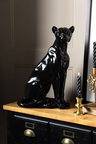 The Beautiful Black Panther Decorative Ornament styled on a wooden surface with some lit candles, a book and a framed artwork.