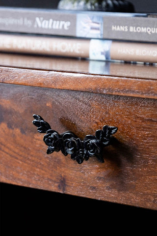 The Beautiful Black Rose Cupboard/Drawer Handle styled on a wooden drawer, with some books in the background.