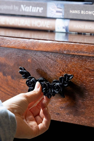 A hand opening a wooden drawer with the Beautiful Black Rose Cupboard/Drawer Handle.