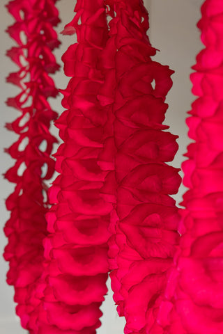The Beautiful Handcrafted Classic Paper Garland in Bright Red shown hanging against a neutral wall. 