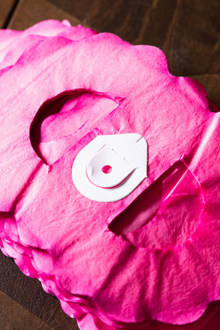 The Beautiful Handcrafted Classic Paper Garland in Hot Pink shown folded up with the paper hanging hook. 