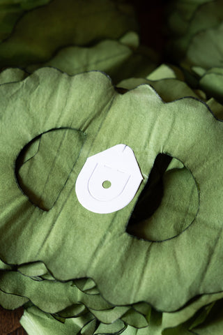 Close-up detail of the end of the Beautiful Handcrafted Classic Paper Garland in Moss Green, showing the paper hanging hook. 