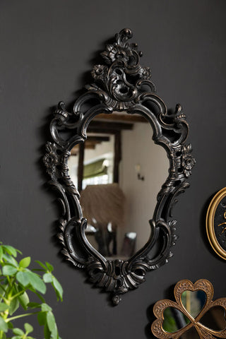 The Beautiful Ornate Black Wall Mirror shown on a black wall. 