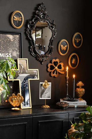 The Beautiful Ornate Black Wall Mirror shown in a gothic glam scene, with other black and gold vintage wall art shown on the walls above a sideboard. 
