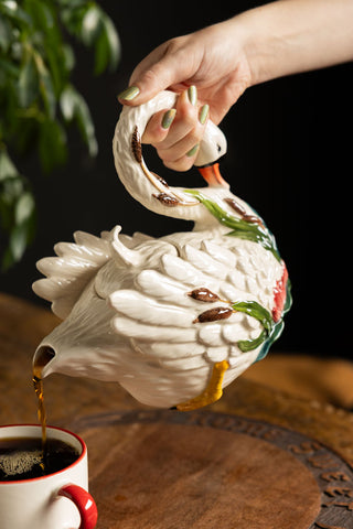 Someone pouring tea from the Beautiful Painted Swan Teapot into a mug.