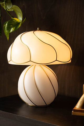 The Beautiful Mushroom Hayworth Table Lamp displayed on a sideboard with a plant and ornament.