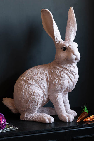 The Bertie The Large Pink Easter Bunny Ornament styled on a black sideboard with some easter decorations.