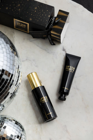 The After Party Hand & Body Beauty Cracker with its contents, displayed on a white marble surface with some disco balls.