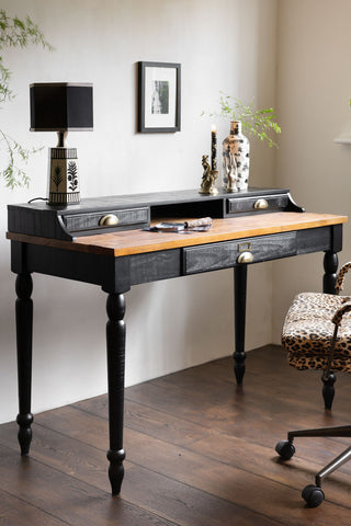 Black Apothecary Desk With 3 Drawers shown in a neutral room with a leopard office chair and monochrome accessories. 