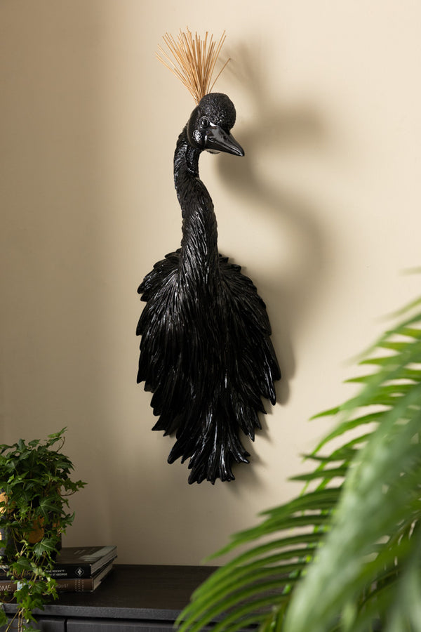The Black & Gold Peacock Wall Art displayed on the wall above a sideboard, styled with some accessories and some plants.