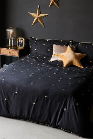 Lifestyle image of the Black Falling Star Duvet Cover and Pillow Case Set displayed on a bed and styled with various home accessories.