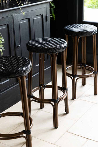 three rattan bar stools against a wooden sideboard indoors.