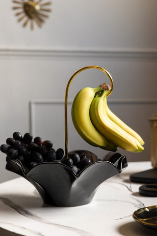 Black Umbrella Fruit Bowl Shown with grapes inside and a bunch of bananas hanging from the handle. 