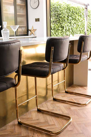 Detail image of the Black & Gold Faux Leather Retro Curve Bar Stool in a luxury kitchen with a gold kitchen island.
