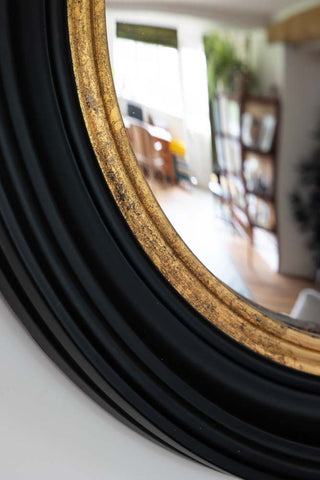 Close up image of black and gold framed convex mirror showing the rim detail