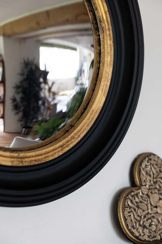 A closer image of black and gold framed convex mirror showing the curve of the mirror
