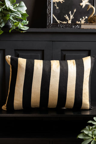 The Black & Gold Stripe Cushion Cover shown head on on a black bench. 