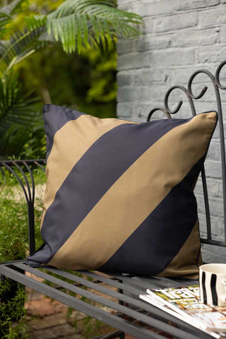 Lifestyle image of the Black & Green Stripe Outdoor Cushion on garden bench.