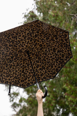 The Black & Leopard Print Umbrella held up in the air in the rain. 