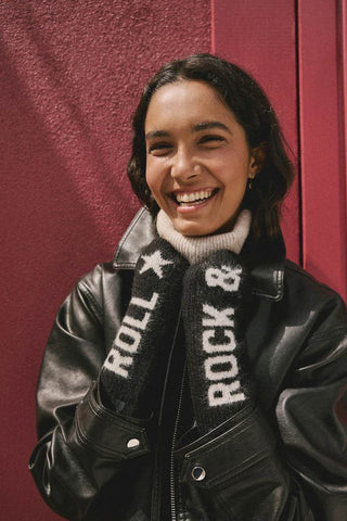 The Black & White Rock 'N' Roll Handwarmers being worn by a smiling model, standing in front of a burgundy background.