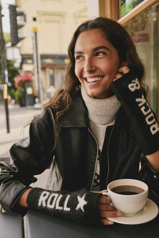 The Black & White Rock 'N' Roll Handwarmers being worn by a model having a coffee outside a cafe.