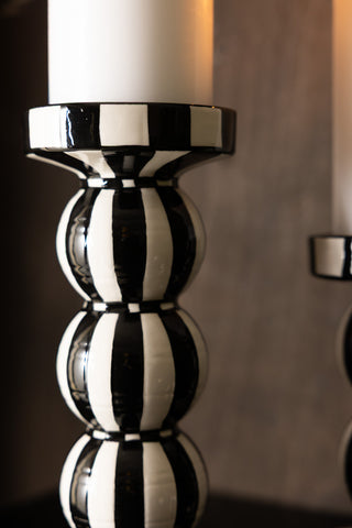 A detailed image of the tall black and white striped candle holder, styled on a dark surface with a pillar candle inside