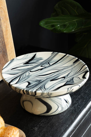 The Black & White Marbled Cake Stand on a dark surface.