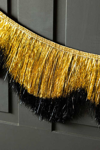 Close-up of the Black & Gold Scalloped Tinsel Garland on a black background.