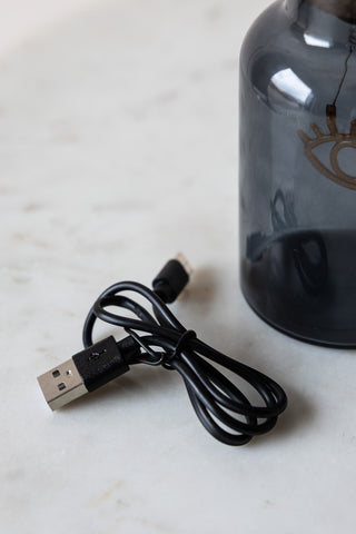 The cable supplied with the Blue Eye Neon Bottle Light on a white surface, next to the bottle.