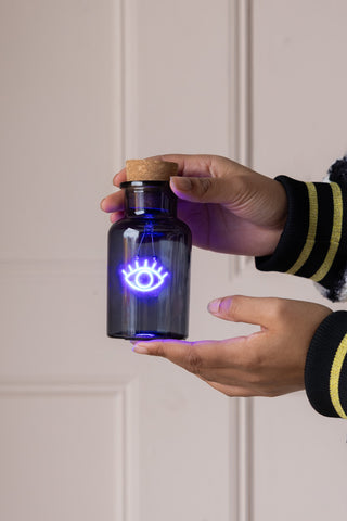 The Blue Eye Neon Bottle Light being held in a model's hands.