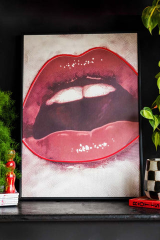 Bold Red Lip Neon Wall Art shown against a black wall with plants styled around the neon wall light. 
